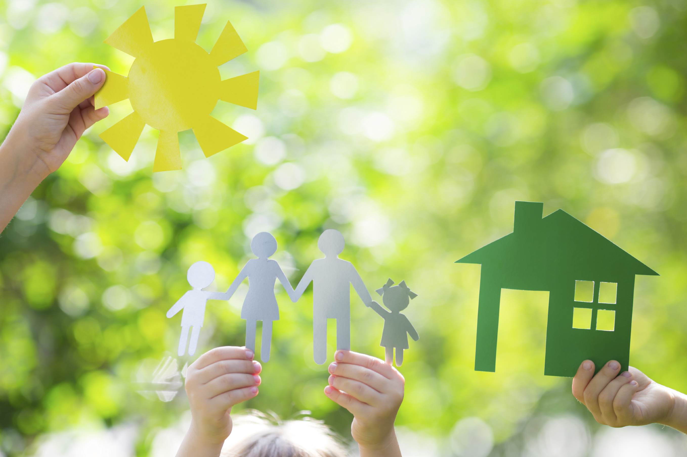 Ecology house and family in hands against spring green background